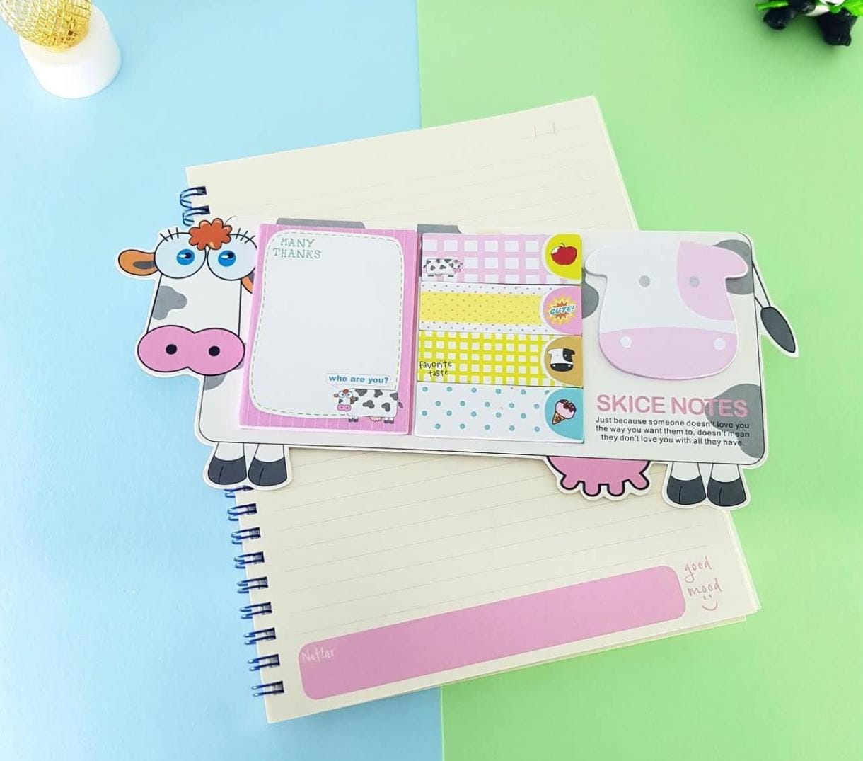 Notebook with cartoon cow design bookmarks on a colorful background