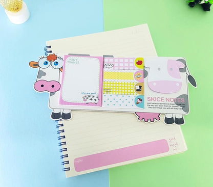 Notebook with cartoon cow design bookmarks on a colorful background