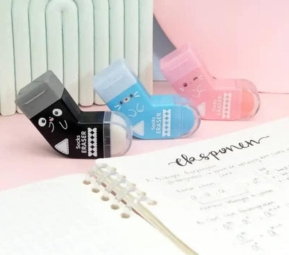 Three colorful erasers on a surface with a piece of paper and a pen.