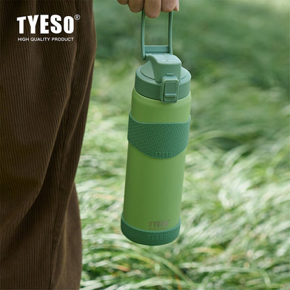 Green water bottle held by a person in a grassy outdoor setting with TYESO branding.