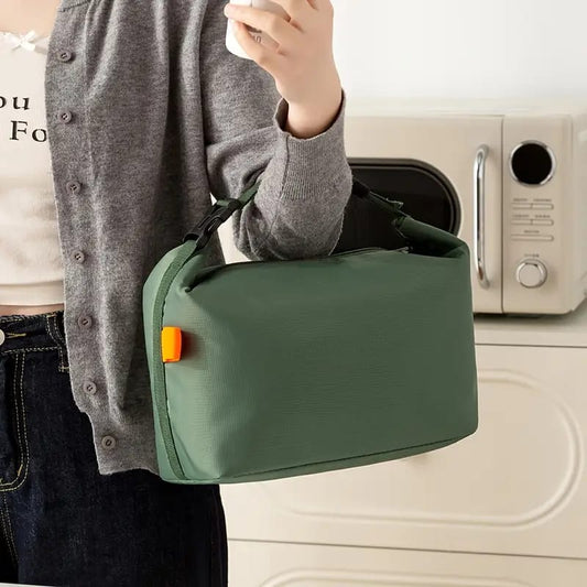 Person holding a green bag with an orange tag in front of a washing machine.