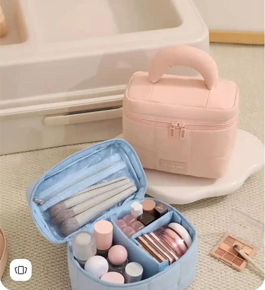 Two cosmetic bags, one pink and one blue, with makeup items inside on a light surface.