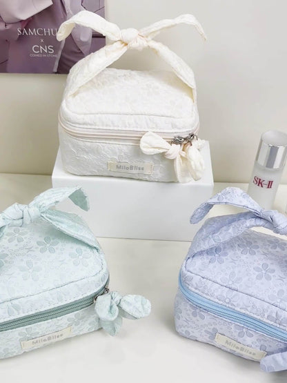 Set of three lace-trimmed cosmetic bags with a bottle of SK-II on a white surface.