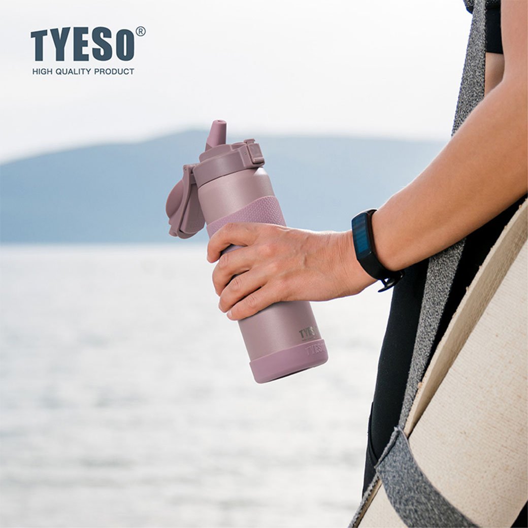 Person holding a purple TYESO water bottle with a blurred natural background