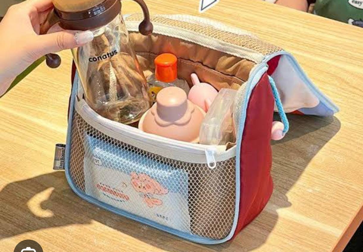 Portable diaper bag with baby bottles and supplies on a wooden surface