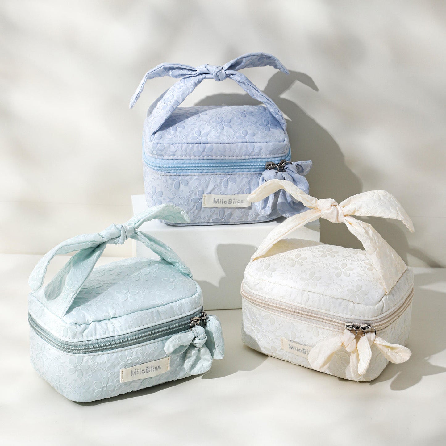 Three small, quilted bags with ribbon ties on a light background