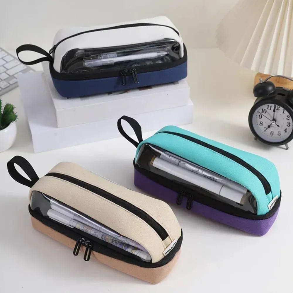 Three transparent pencil cases in different colors on a desk with stationery items.