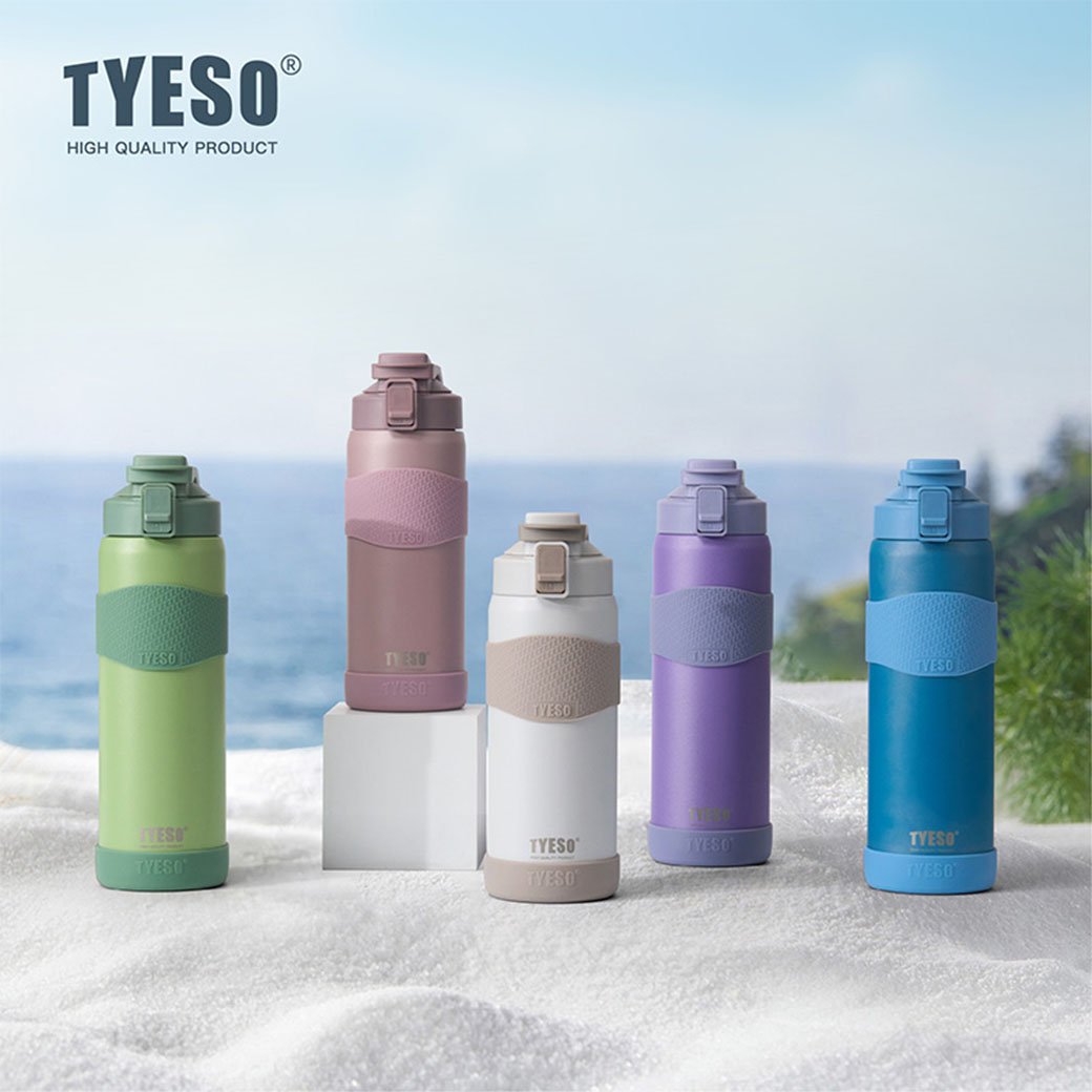 Five colorful TYESO water bottles on a beach with ocean view