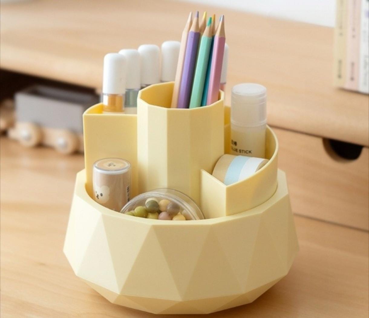 Yellow geometric desk organizer with stationery items on a wooden surface